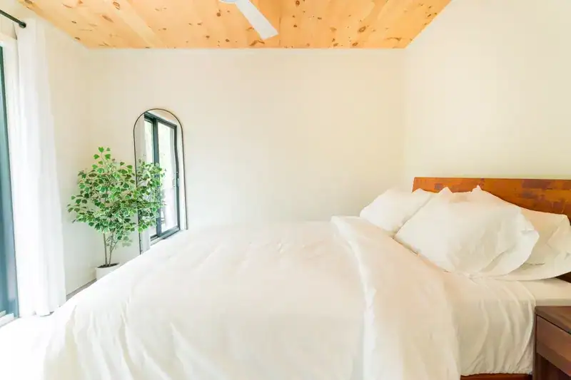 Bright bedroom with timber bed and white linens