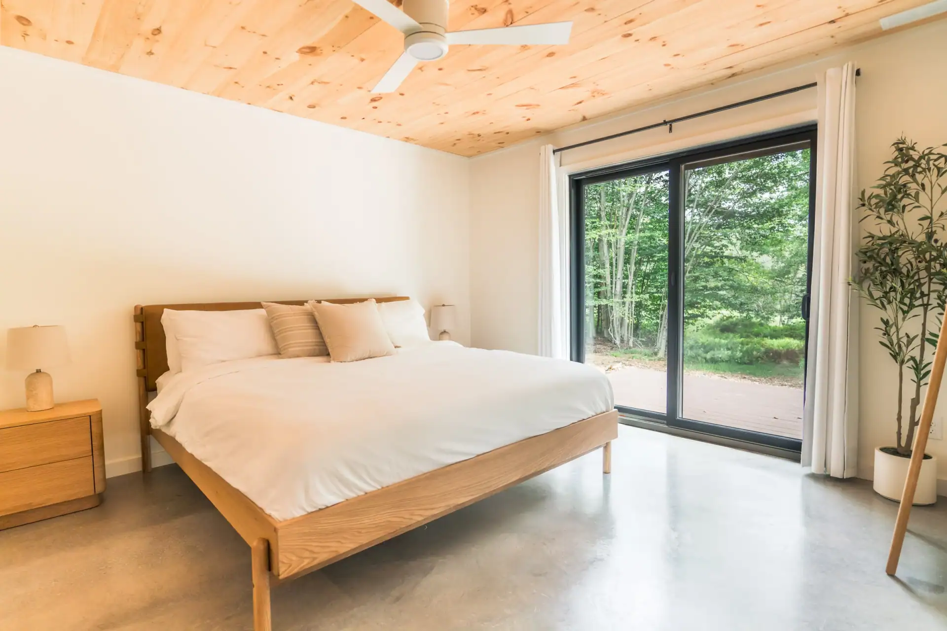 King bedroom with vaulted pine ceiling and doors opening onto the deck