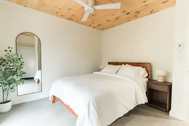 Bedroom with a round mirror and vaulted pine ceiling