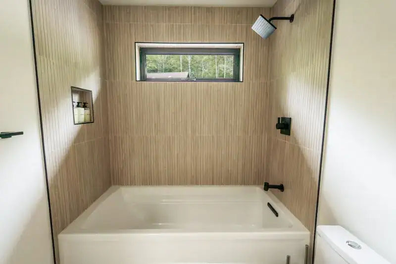 Bathtub and shower beneath a high window