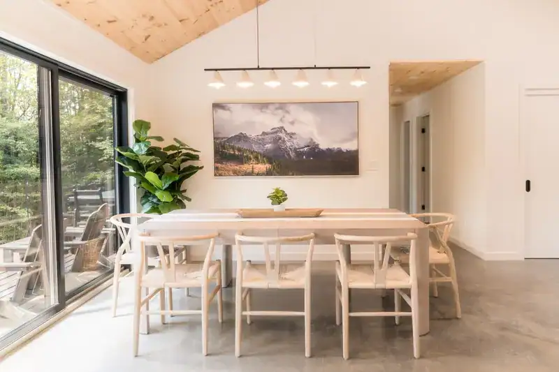 Dining table and mountain artwork beside deck doors