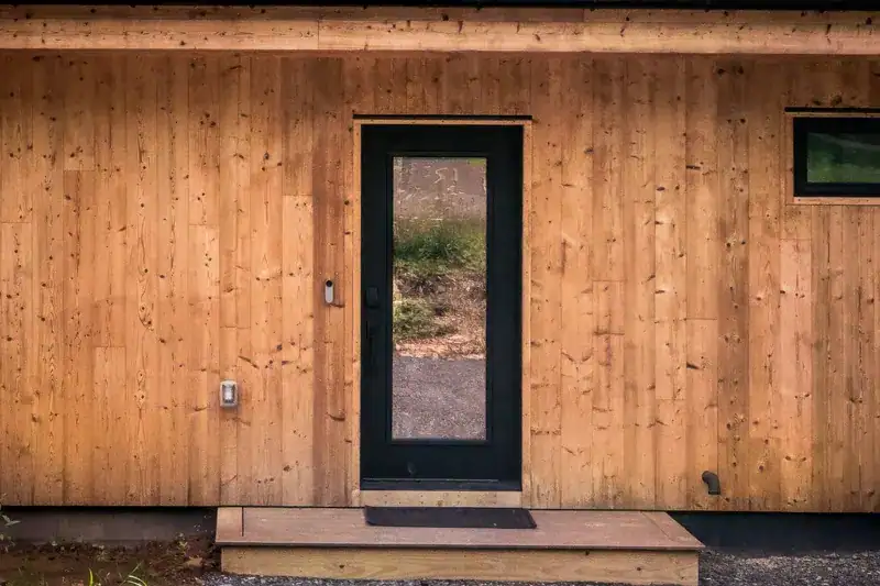 Black front door framed by cedar siding