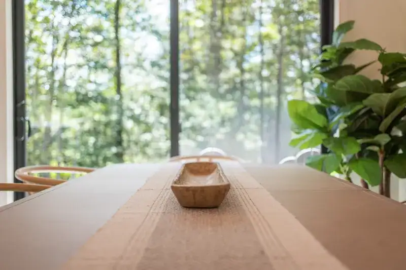 Wooden dining table beside forest-facing windows