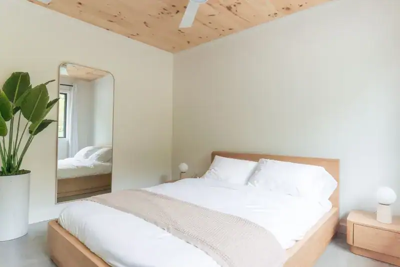 Bedroom with mirror, plants, and timber bed
