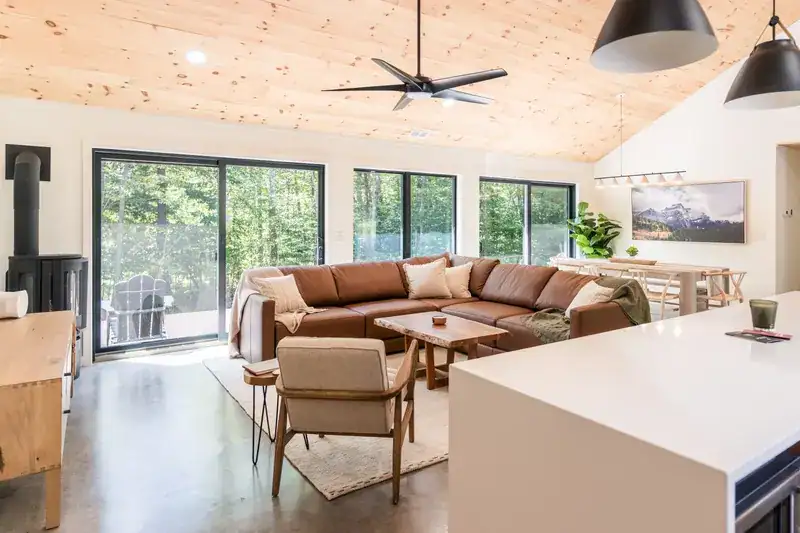 Open living room with sectional, stove, and deck doors